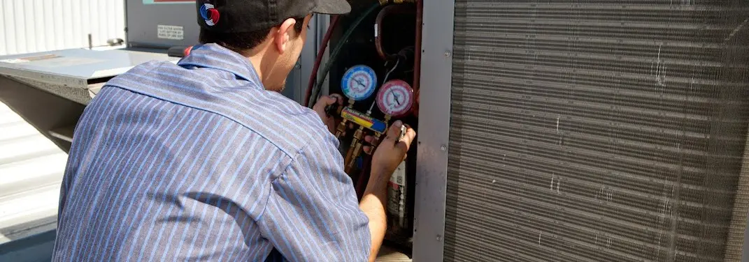 HVAC technician servicing a condenser unit in Broadalbin