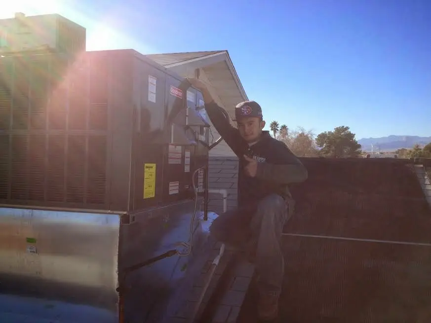 HVAC technician performing AC Tune-Up on a rooftop unit in Broadalbin